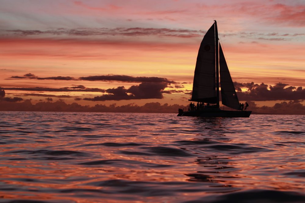 a sunset behind a boat on a body of water