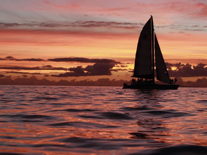 a sunset behind a boat on a body of water