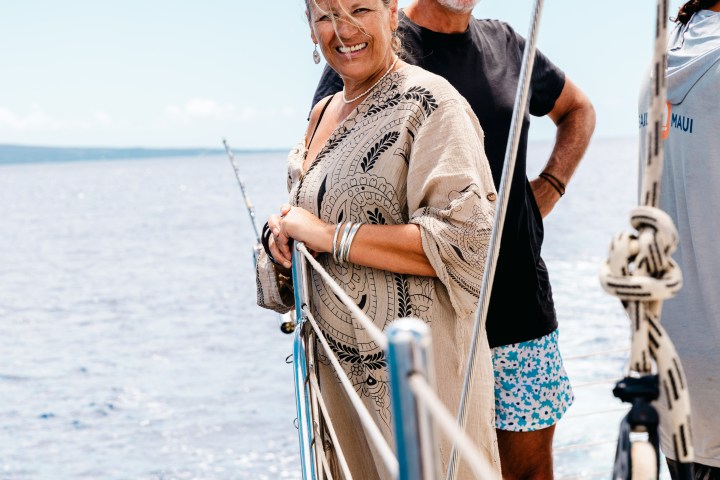 Smiling couple on a sailboat with ocean in the background.