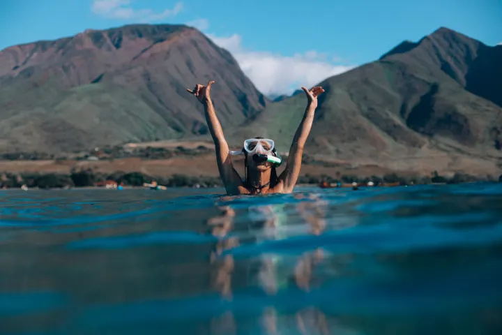 a person swimming in a body of water with a mountain in the background