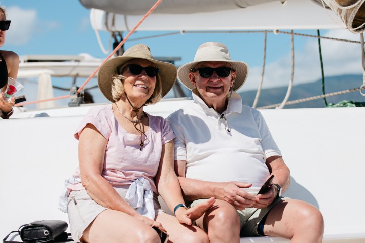 Smiling couple in sun hats sitting on a boat.
