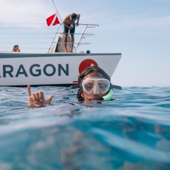 Person snorkeling near boat on water surface with 'PARAGON' sign.