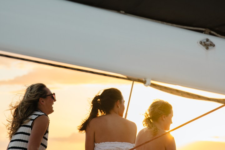 Three women sit on a boat at sunset, enjoying the view.