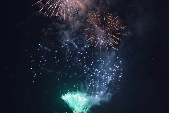 Fireworks display over a body of water with reflections at night.